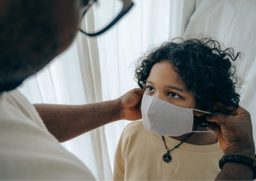 Child getting mask adjusted by an adult.