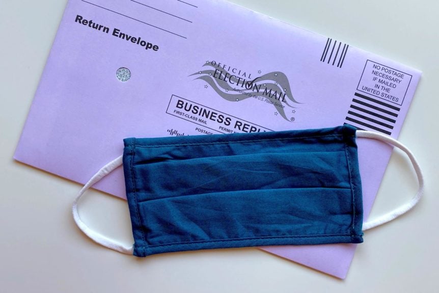Cloth facemask in front of a mail-in ballot.
