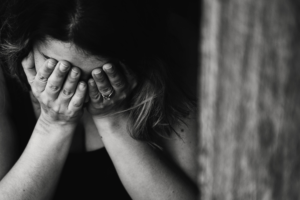 Woman with her head down and covering her face with her hands.